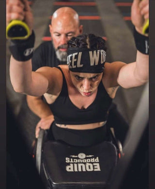 Jesi Stracham using a Ski Erg at the 2023 WheelWOD Games Mark Harris is her handler behind her.