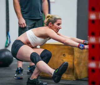 Kym Dekeryel Doing Pistol Squats at the 2021 WheelWOD Games in a white sports bra and black shorts
