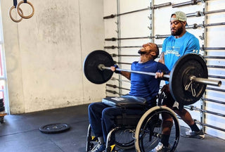 man in wheelchair lifting a barbell with LapMat on his legs