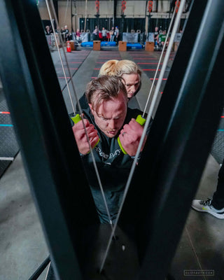 Josh Young Using a Ski Erg at the 2022 WheelWOD Games Nicky holding his chair steady