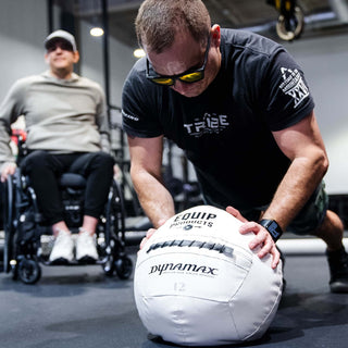 A Visually Impaired Man on how knees leaning on an Equip - Dynamax White Wall ball in a gym