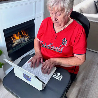 Senior person using a laptop with a LapSecure Desk in a home setting with a fireplace in the background