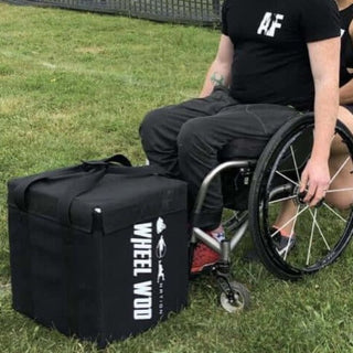Wheelchair Athlete Josh young in a wheelchair about to pickup a square cushioned box made