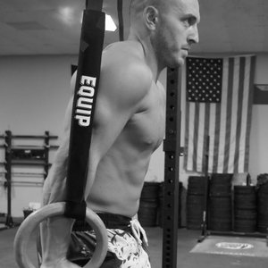 Athlete Shane McBride on the rings in a black and white picture and Shane is facing right