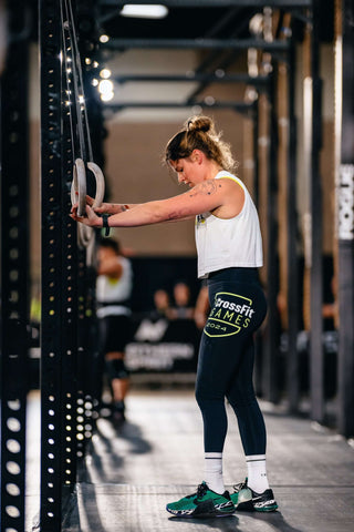 Lady contemplating a workout in a gym holding rings in her hands for ring dips...