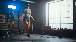 Lady jumping rope / Multi Ropes™ in a gym setting with a huge box pane style window letting light shine on her left side.