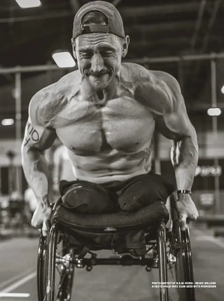 Mike Egan in a wheelchair pushing hard in black and white