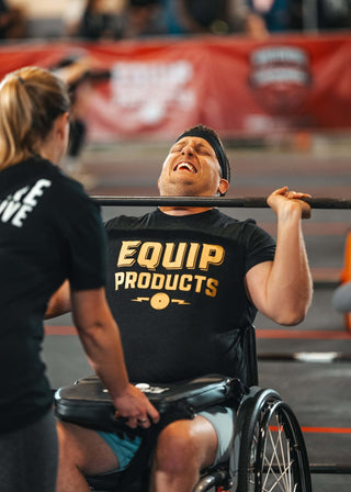 Wheelchair athlete using a barbell with a LapMat™ and an Equip Products shirt on.