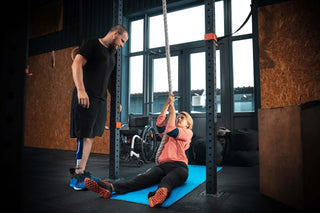 Strong wheelchair athlete pulling from the ground to a rope climb