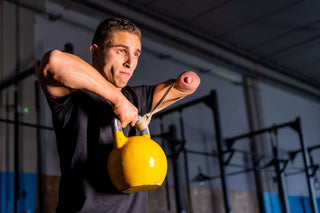 Xabier Osa missing left arm below elbow and limited fingers on his right hand lifting a kettle bell in a dark gym setting.