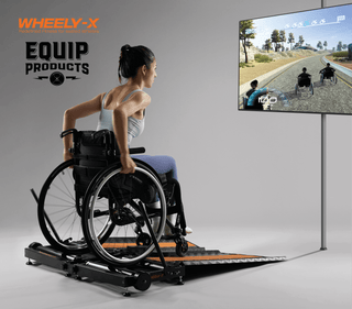 Lady using the Wheel-X Trainer in front of a large tv screen for itneractivity