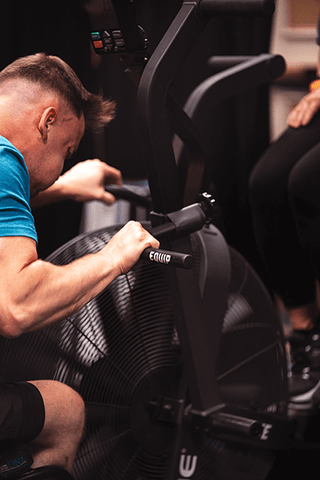Seated Athlete Using Equip Bike Handles and Echo Flip Monitor Mount on the Rogue Echo Bike