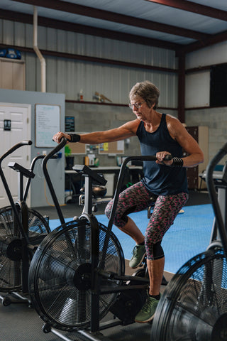 Older lady using an assault bike in a CrossFit gym