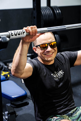 Visually impaired man holding a barbell with barbell markers from Equip Products on it.