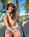 Jesi Stracham on a beach wearing a cute straw hat and holding her hair out of her face