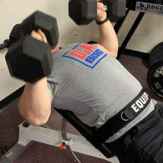 Kevin Ogar doing dum bell presses on a bench using the Equip Products body strap to stabilize 