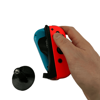 UNI JoyCon Single Hand Adapter for peole who want to game with only one arm. Red and blue controllers in the black stand on a white background hand holding JoyCons