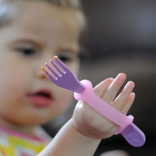 Child using a purple fork attached to a pink silicone EazyHold Teacher & Therapist 7-Pack grip aid.