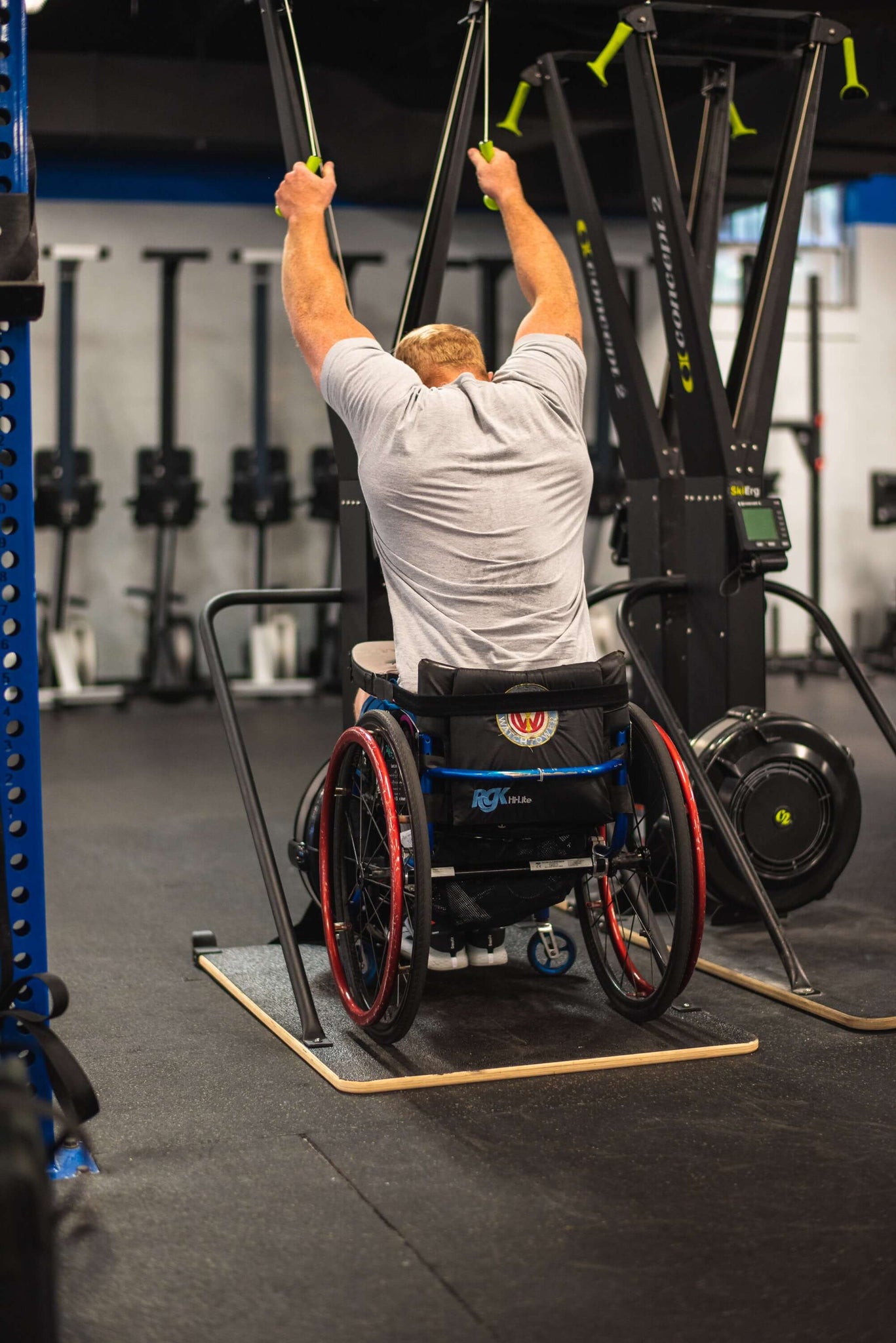 Wheelchair Athlete Kevin Ogar Using a Concept2 Ski Erg with his back facing you in a gym setting equip wider base