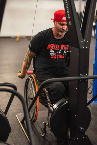 Wheelchair Athlete "GOAT" Stouty on Concept2 Ski Erg Using Equip's Adaptive Wider Base pictured looking at his face on the erg.