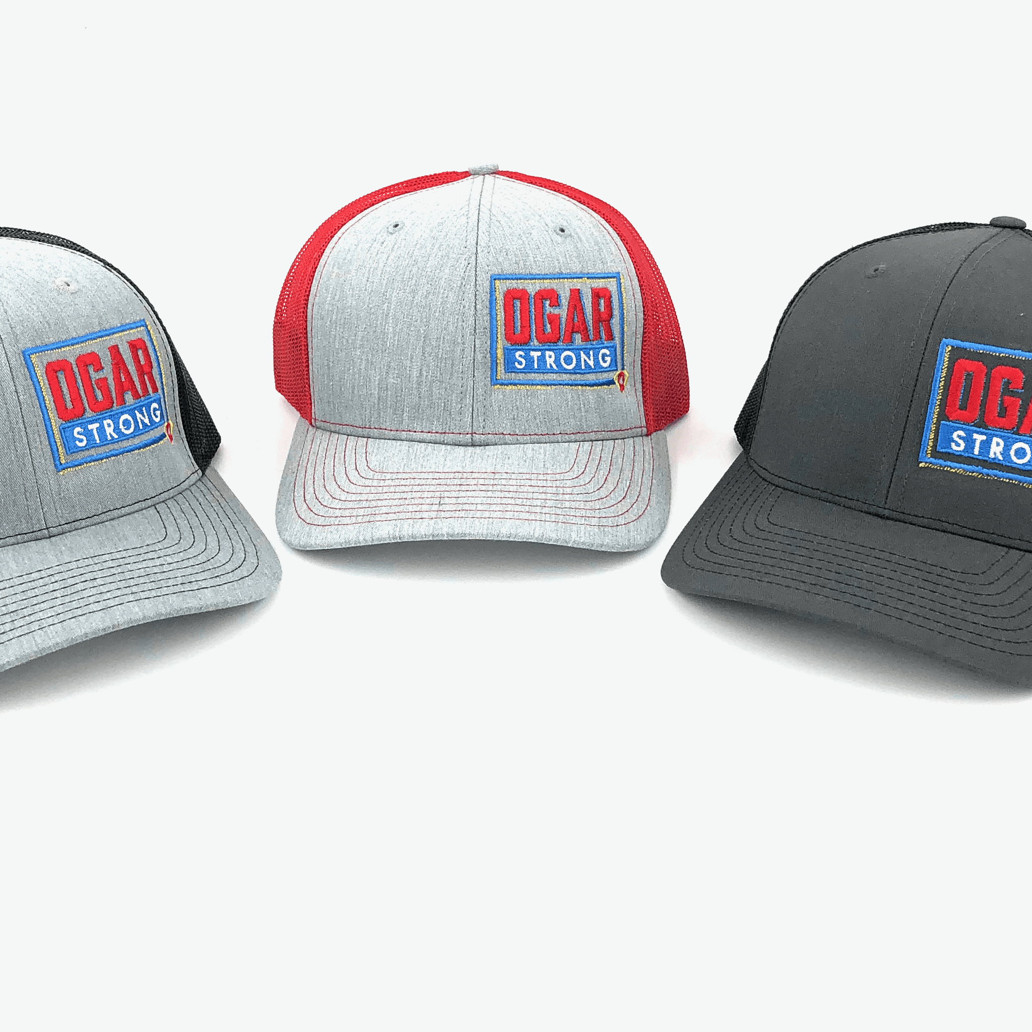 Three mesh style trucker hats in black mesh - grey front panel, red mesh - grey front panel and black mesh and black front panel all have the Ogar Strong Logo embroidered on the front left panel