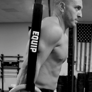 Athlete Shane McBride on rings with Equip Ring Rash Guards around the straps and the Equip name in white vertically